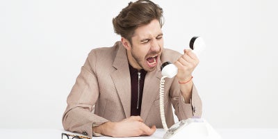 man yells at phone handset