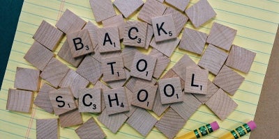 legal pad with a pile of wooden letters on it that spell out back to school