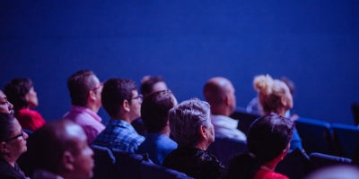 group of people sitting in a theater facing a movie screen