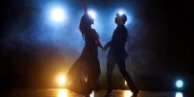 couple dance on stage backlit with lights