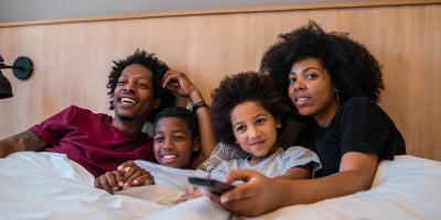 family watching TV together while under the covers