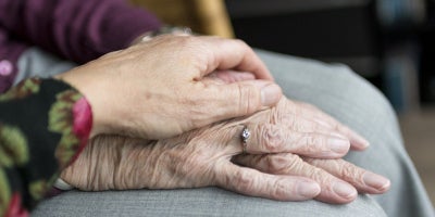 elderly individual holding hands with family