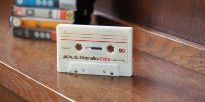 photo of cassette standing upright on table with stack of cassette cases behind 