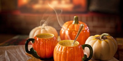 image of hot bevarages in pumpkin shaped mugs surrounded by mini pumpkins