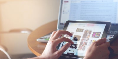 photo of someone using tablet with laptop also in view