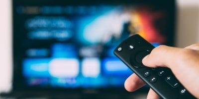 photo of hand holding remote to a smart tv