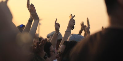 photo of crowd at a concert with their hands up