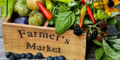 wooden box labeled farmer's market filled with fresh veggies