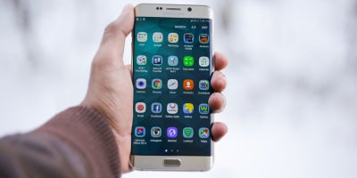 hand holding mobile phone with open screen and app icons showing