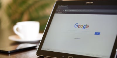 tablet open to search engine google on a desk with a coffee cup