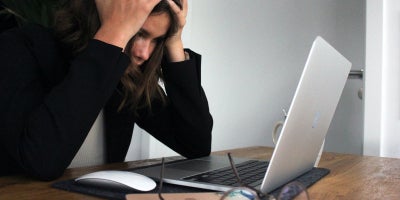 photo of a woman stressed out looking at her laptop overheating