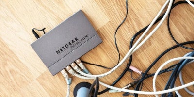 office router sits on a hardwood floor connected to wires