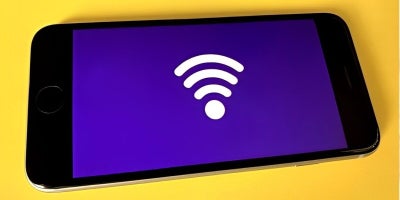 cell phone with a wifi symbol displayed laying on yellow table, blog, need more internet speed