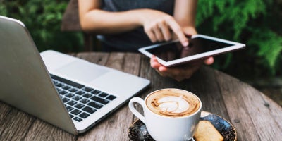 laptop vs tablet for college, tablet vs laptop for college, woman on tablet and laptop with coffee
