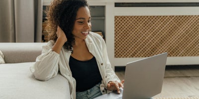 A woman sitting on the floor, using a laptop connected to her home WiFi after installation
