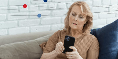 Woman sitting on couch at home while on cell phone with a frustrated look 