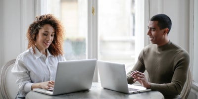 Man and woman using laptops while sitting together at a table