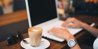 Woman working on laptop with a coffee at a table using public WiFi