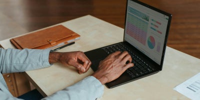 Man adjusting spreadsheets on a laptop.
