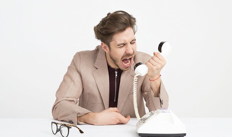 man yells at phone handset