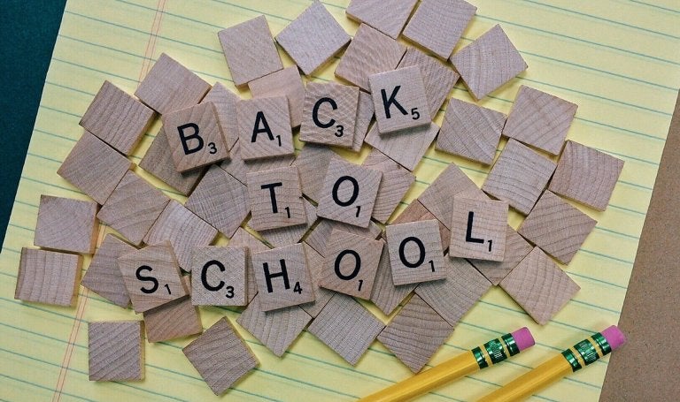 legal pad with a pile of wooden letters on it that spell out back to school