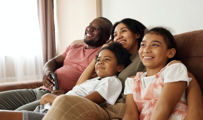 happy family sitting on a couch and watching tv