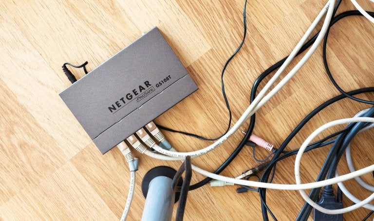 office router sits on a hardwood floor connected to wires