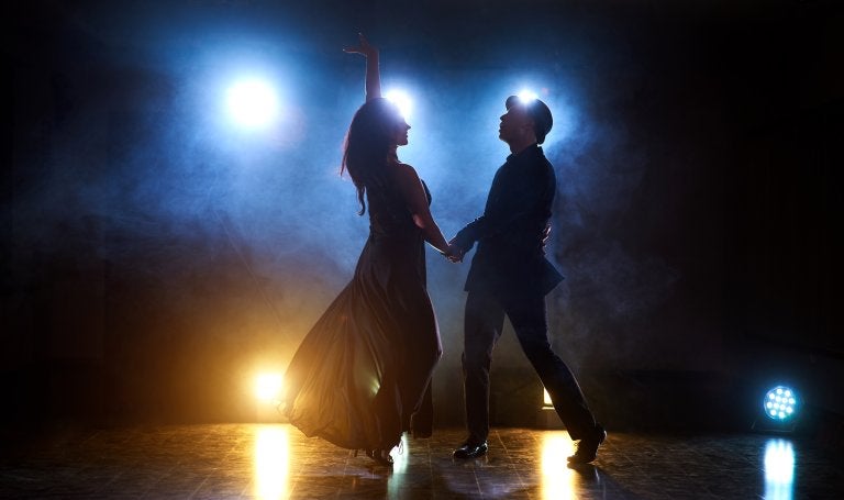 couple dance on stage backlit with lights