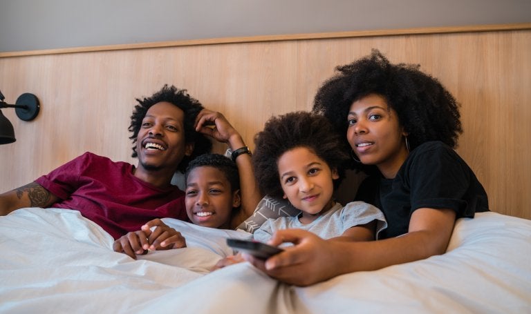 family watching TV together while under the covers