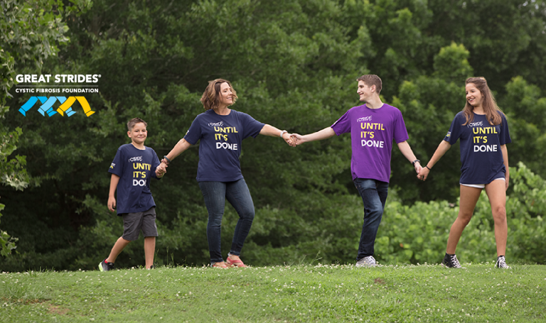 four people walking hand in hand with "I stride until it's done" on their shirts