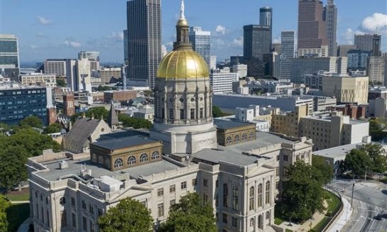 The gold dome of the Georgia Capitol gleams in the sun, in 2022, in front of the skyline of downtown Atlanta.