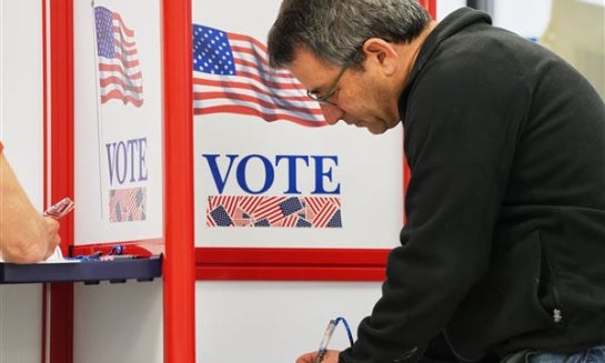 People walk past a sign directing voters on the first day of early voting in Minnesota on Sept. 18 at the Elections & Voter Services building in Minneapolis.