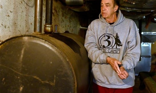 Mark Bain, who is part of the Low Income Home Energy Assistance Program, rubs his hands together as he checks the level on his oil at home in hopes that he will have enough oil to outlast the shutdown, in Bloomfield, Conn. on Oct. 27.