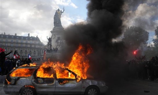 A woman walks her dog past a looted store the day after a demonstration against rising living costs, joining students' grievances, in Paris on Oct. 18.