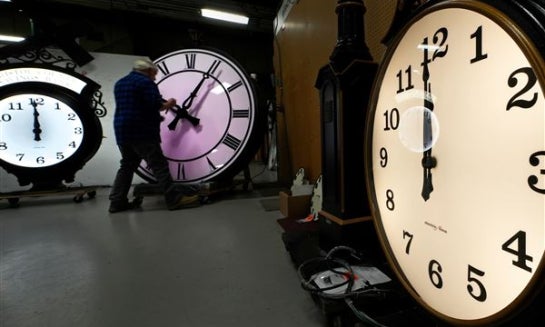 Clockmaker Scott Gow adjusts the hands of a clock at the Electric Time Company, Oct. 30, 2024, in Medfield, Mass.