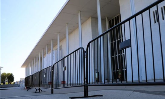 The Kennedy Center, which has been fenced off and closed to the public, is seen through a hole in a covered fence Sept. 17 in Washington.
