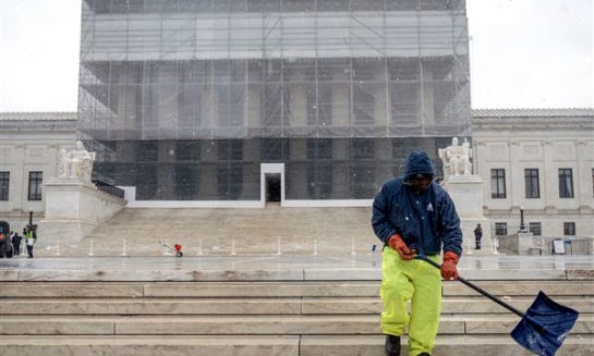 A worker shovels snow and ice in front of the Supreme Court building during the first snowfall of the winter season on Dec. 5 in Washington.