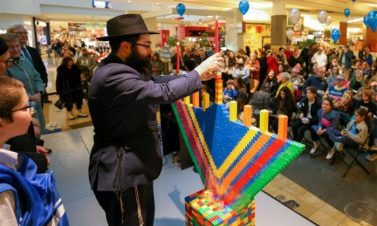 Rabbi Shmouel Matusof places a candle on the Lego menorah during the Chabad House of Greater Toledo’s Chanukah at the Mall event at Franklin Park Mall in Toledo on Dec. 18, 2022.