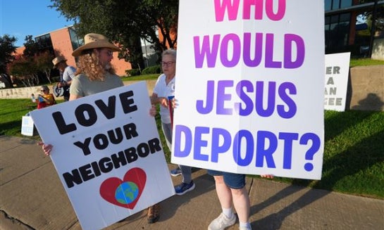 People holds a sign outside the U.S. Immigration and Customs Enforcement (ICE) office during a weekly prayer and protest gathering in Dallas on Oct. 12.