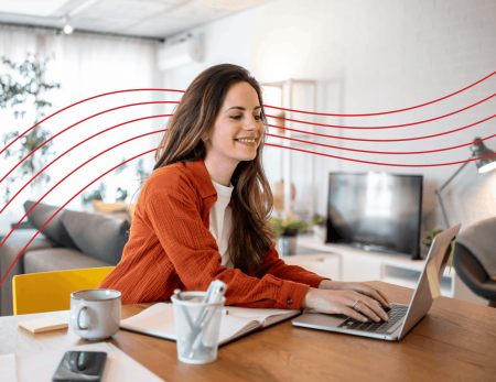 Woman smiling and typing on laptop at desk