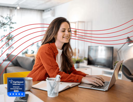 Woman typing on laptop at desk - high speed internet award logo 
