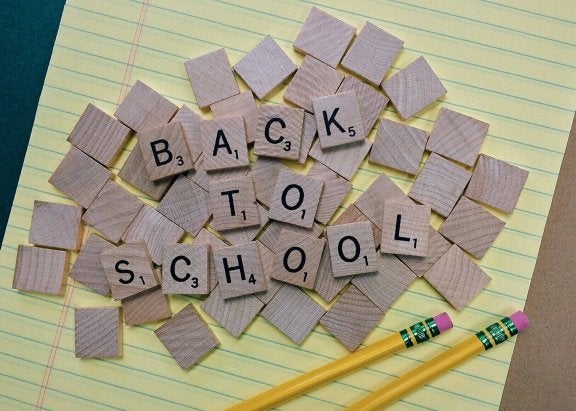 legal pad with a pile of wooden letters on it that spell out back to school