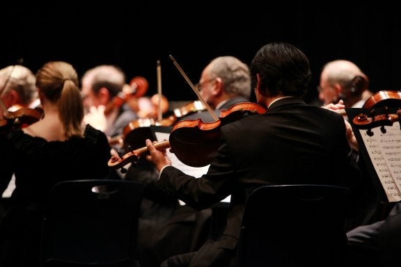 behind view of a symphony orchestra in the violin section