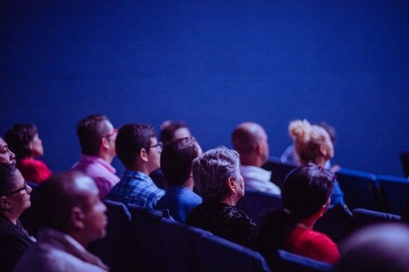 group of people sitting in a theater facing a movie screen