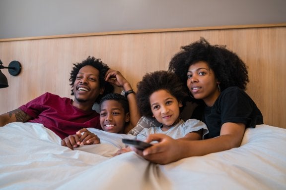 family watching TV together while under the covers