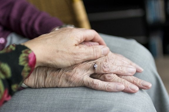 elderly individual holding hands with family