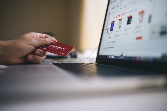 image of person holding credit card next to laptop with shopping site