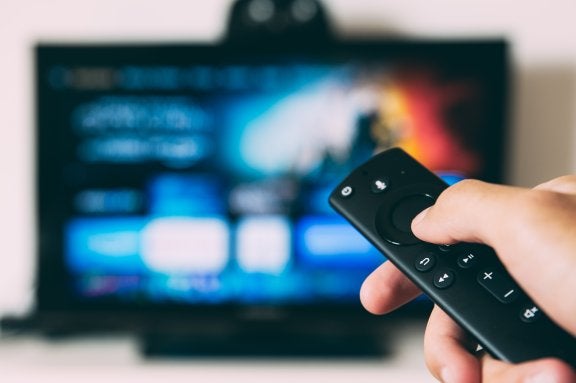 photo of hand holding remote to a smart tv