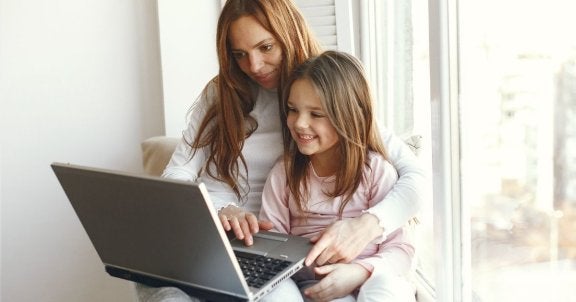mother and daughter sit in a windowsill using a laptop, back to school laptop