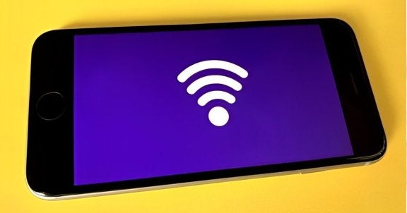 cell phone with a wifi symbol displayed laying on yellow table, blog, need more internet speed